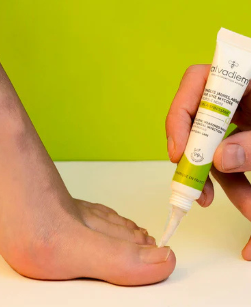 Visuel d'application du Soin Assainissant Ongles, un soin anti fongique avec une application pinceau sur le gros orteil d'un pied. 